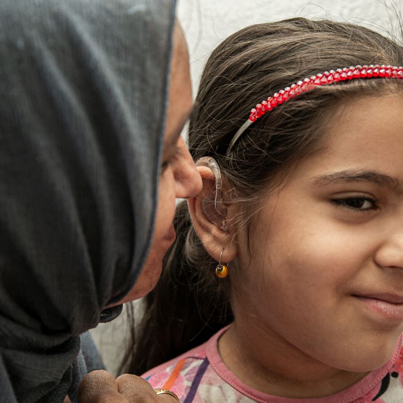 Asma talks to her daughter Rimas, who can now hear her after receiving a hearing aid. The DRC assisted Rimas and her brother Mohammad in obtaining disability reports and advocated for them at the case level. The team also referred their case to another humanitarian organization, which provided the hearing aids and supported the children during the fitting process.