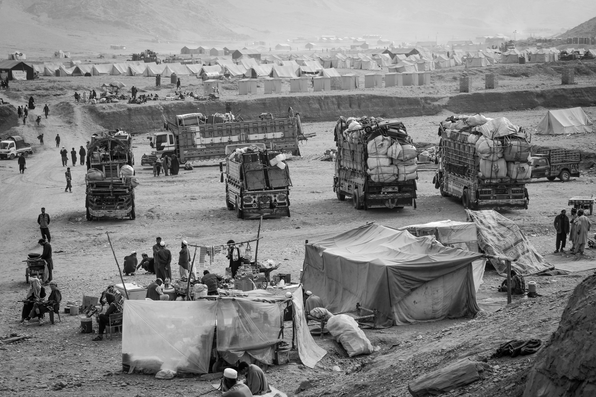 Trucks with belongings of several families are waiting for Afghans to obtain some assistance and define the place they will go to settle. Torkham Reception Center, Nangarhar, 23 November 2023. @DRC, Manon Radosta 