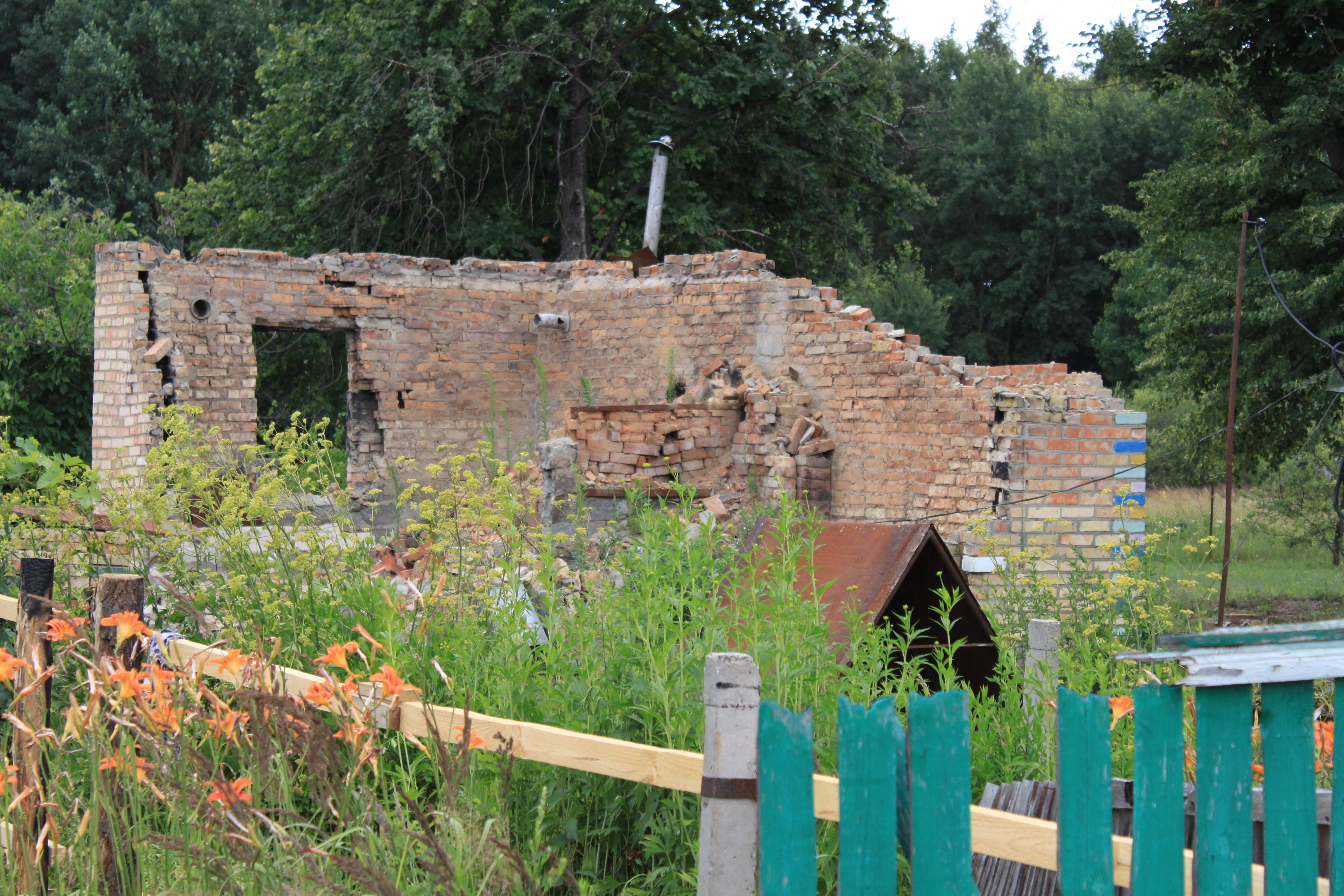 A destroyed house in Zakharivka village next to the field where deminers work. After the territory of the village is cleared, locals can come here and start rebuilding their homes.  ©DRC Ukraine, Kyiv Oblast, 2023, Volodymyr Malynka.