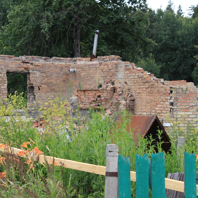 A destroyed house in Zakharivka village next to the field where deminers work. After the territory of the village is cleared, locals can come here and start rebuilding their homes.  ©DRC Ukraine, Kyiv Oblast, 2023, Volodymyr Malynka.