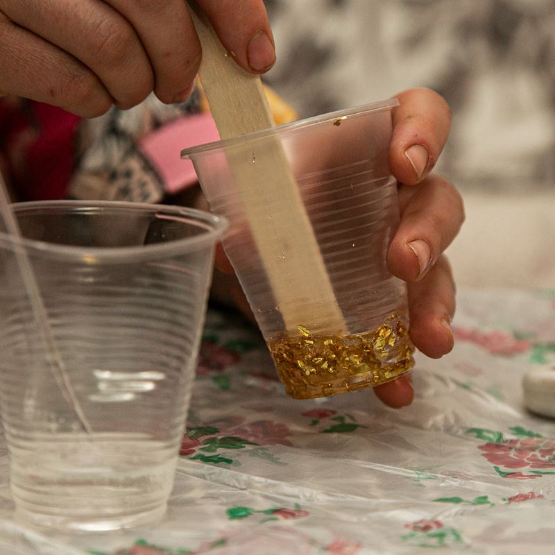 Rochan is working on her epoxy resin handicrafts. She is mixing golden flakes into resin.
